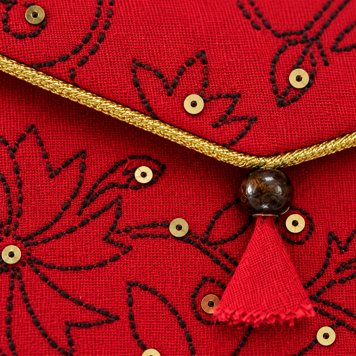Close-up of embroidered floral detail and gold trim on red Khadi