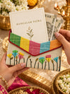 Hand holding shagun envelope with card and cash